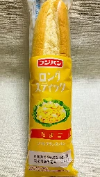 フジパンのロングスティック『たまご』味。黄色いパッケージに商品名とレタス付きたまごサラダのイラスト入り。上部に焼き色の付いたソフトフランスパンが透明フィルム越しに見える。