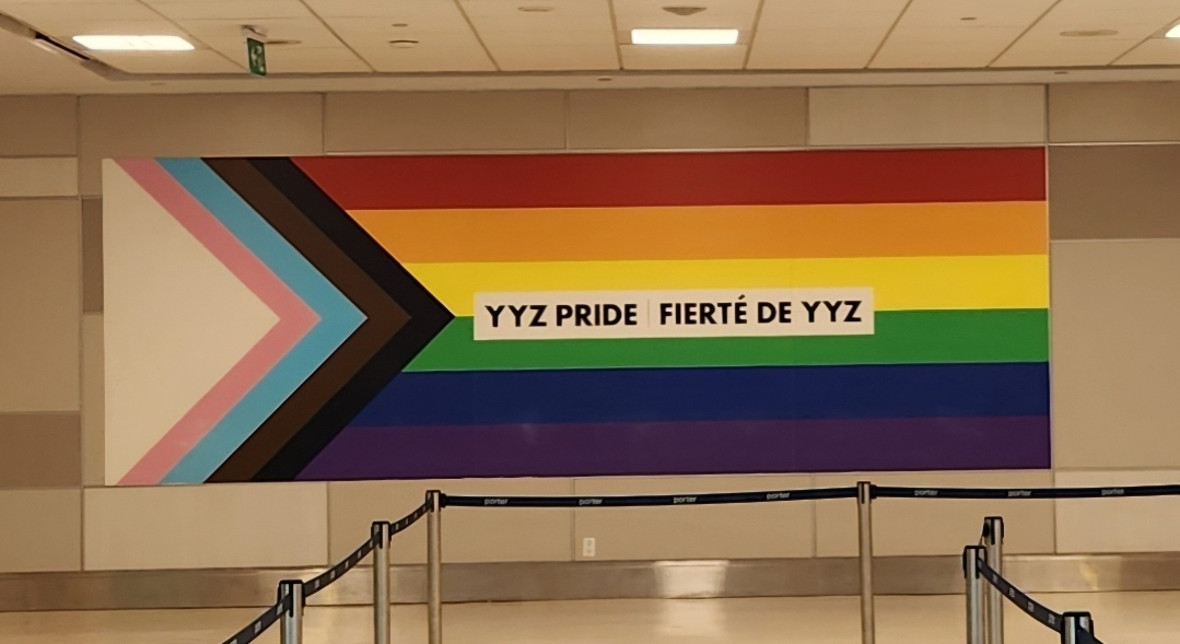 Inclusive Pride Flag mural in Pearson Airport with "YYZ Pride" in English and "Fierté De YYZ" printed across the middle.